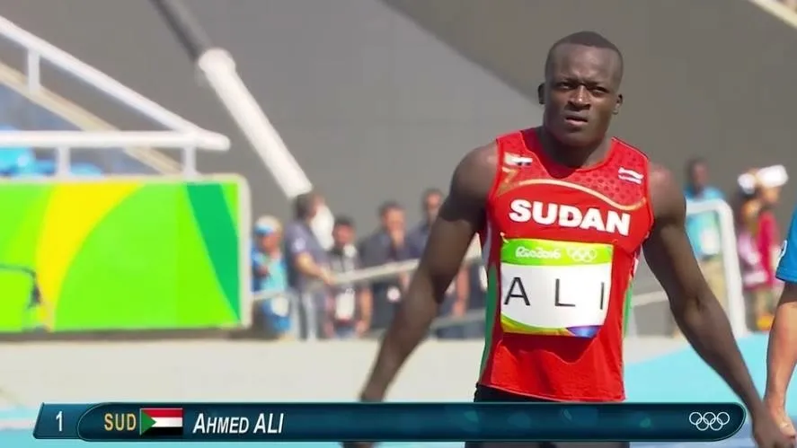 Ahmed Ali in Sudan's red kit, wearing his ALI bib with the Rio 2016 Olympic rings, on the track at the Olympic Games.