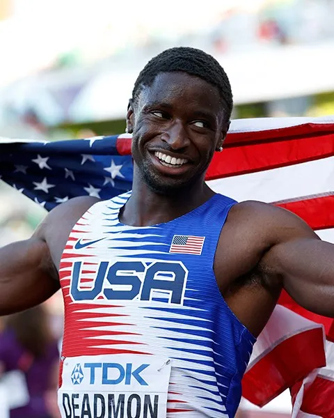 Bryce Deadmon smiles with the American flag draped over his shoulders after winning gold at the World Championships.