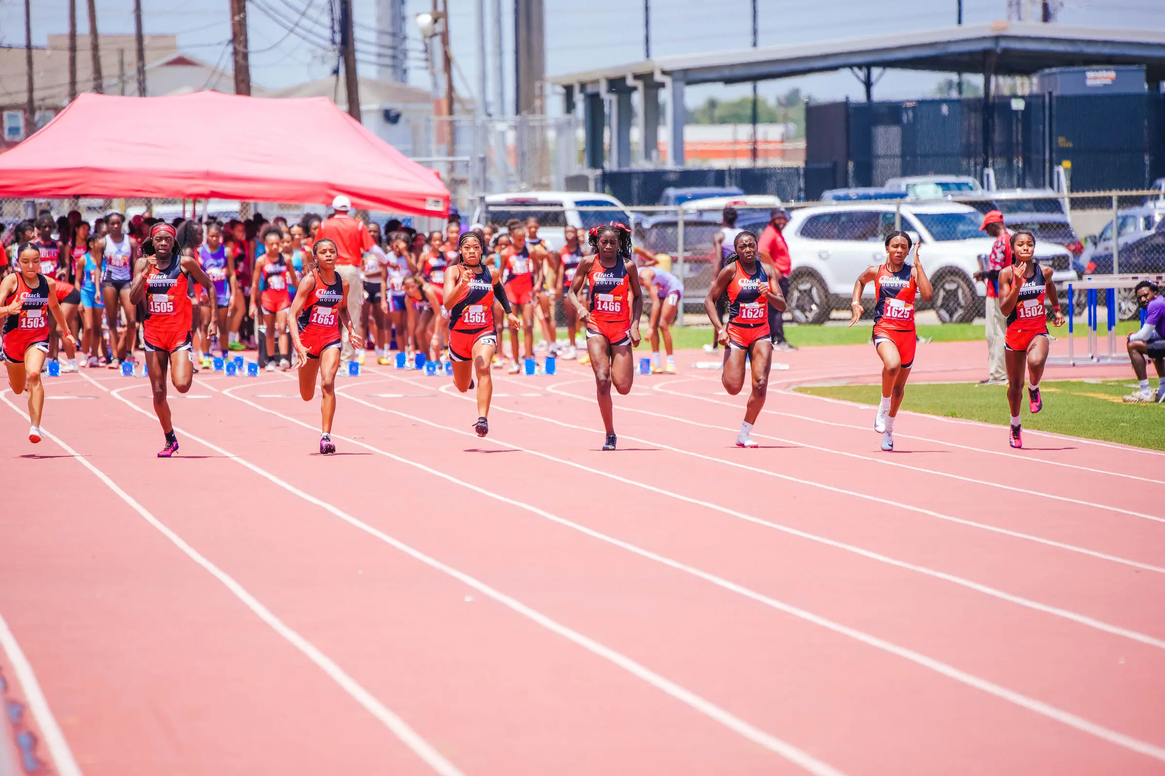 Track Houston girls sprinting off the start line at a summer meet.