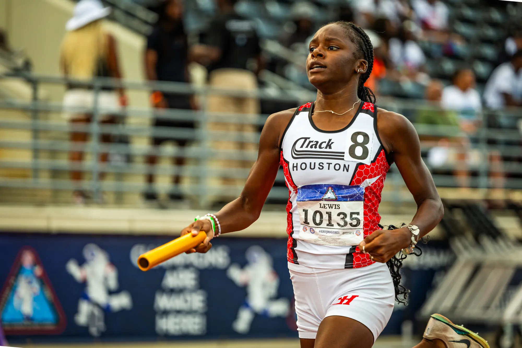 A Track Houston relay runner brings home the baton in front of a championship crowd.