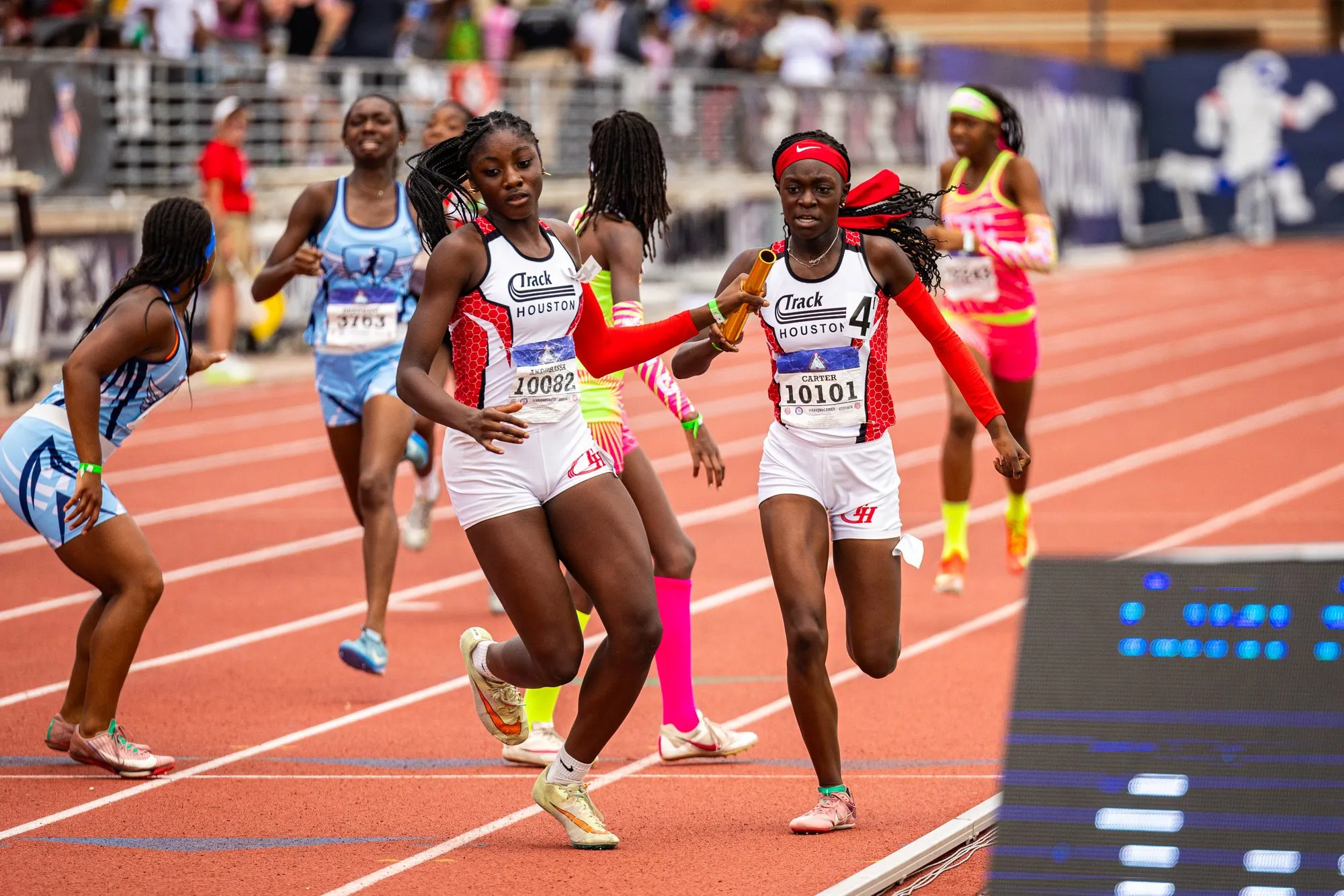 Chloe Carter passes the baton to Maryann Akpobassa mid-race for Track Houston at a championship meet.