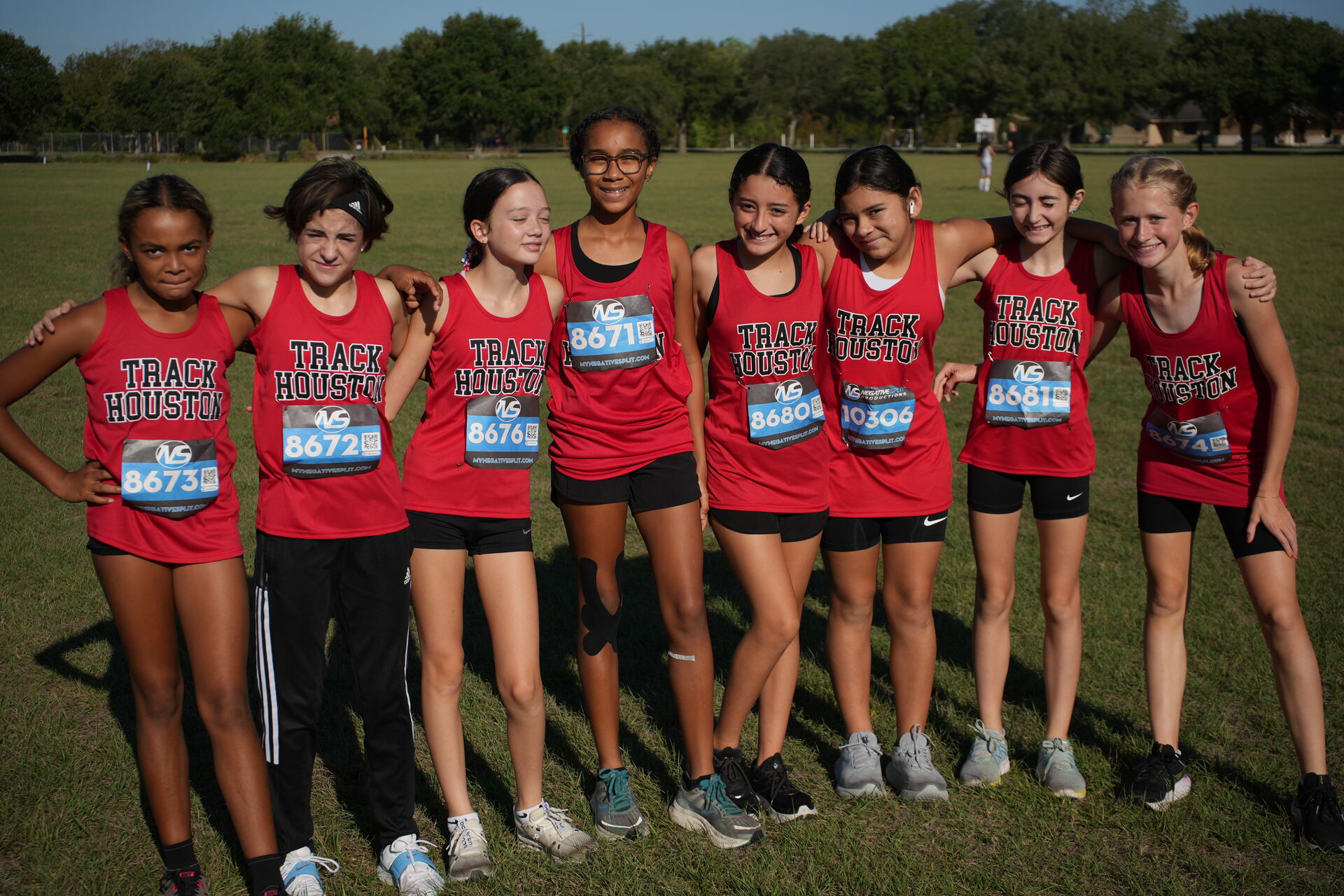 Track Houston girls cross country team arm in arm before a race.